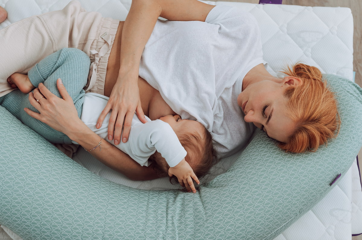 Nursing mother with her baby and a Träumeland nursing pillow in the design fish mint breastfeeding-mother-with-traeumeland-nursing-pillows