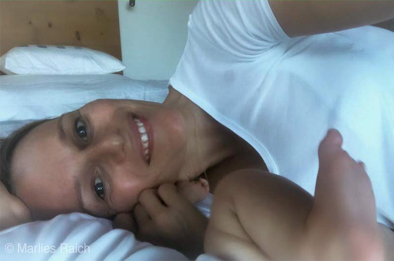 Marlies Raich mit Baby auf dem Bett liegend Marlies Raich mit Baby auf dem Bett liegend