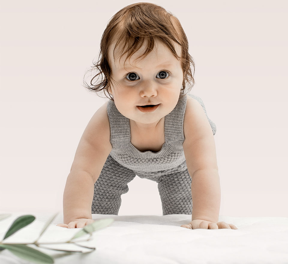 Bébé en grenouillère grise sur fond beige Bébé en grenouillère grise sur fond beige