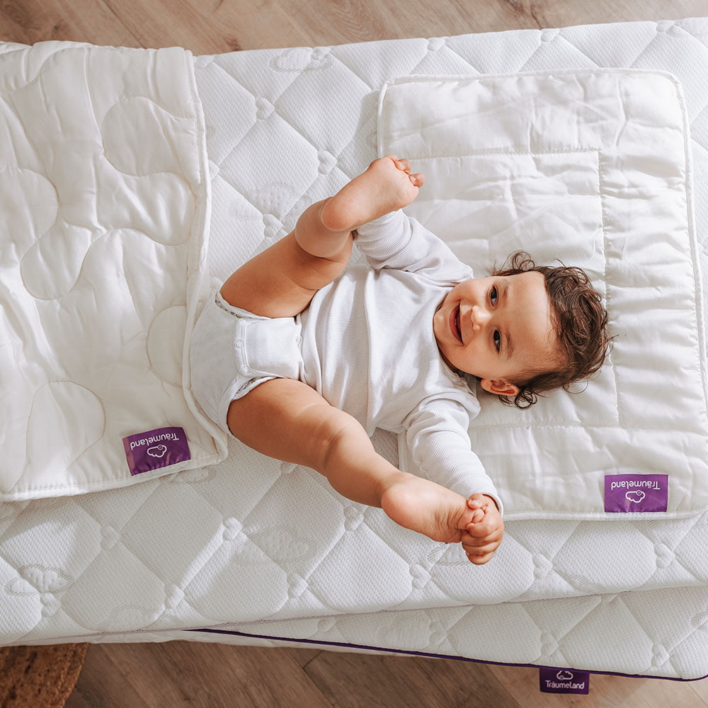 Baby im Bett mit Babydecke und Babykissen babybett-babydecke-babykissen-kind