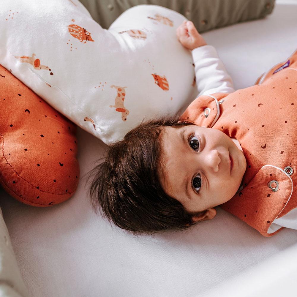 Baby in the cot with Träumeland cuddle cushion in heart shape