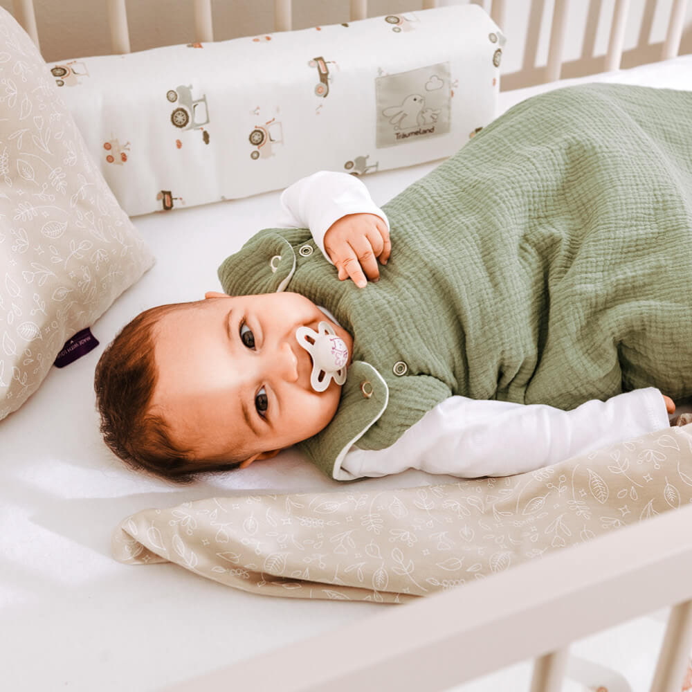 Bebé con chupete y saco de dormir en cuna