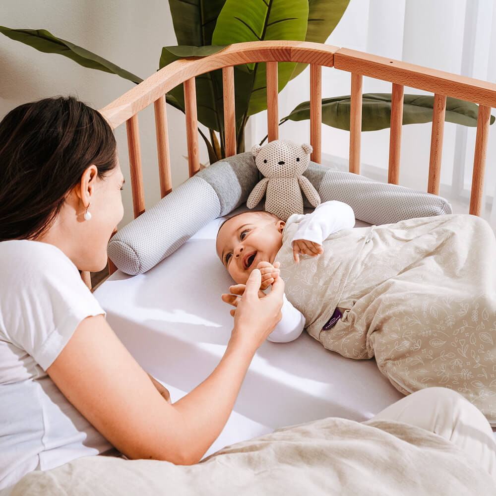 Baby in the co-sleeper bed with a nest-reducer and a sleeping bag of Träumeland