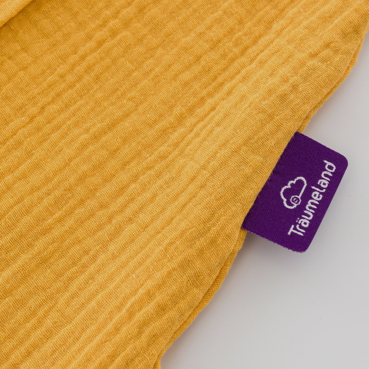 Sommerschlafsack aus Baumwollmusselin in senfgelb Detailfoto vom Träumeland-Etikett