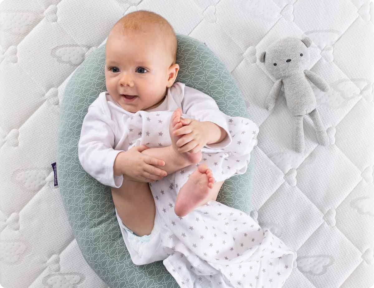 Kind-Augen-Hand-Mund-Fuss-Koordination-auf-Matratze baby-spielt-barfuss-auge-hand-koordination-foerdern